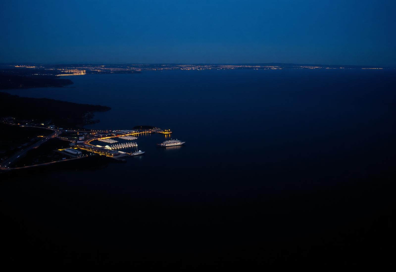 A distant harbor at dusk, small lights along the coastline